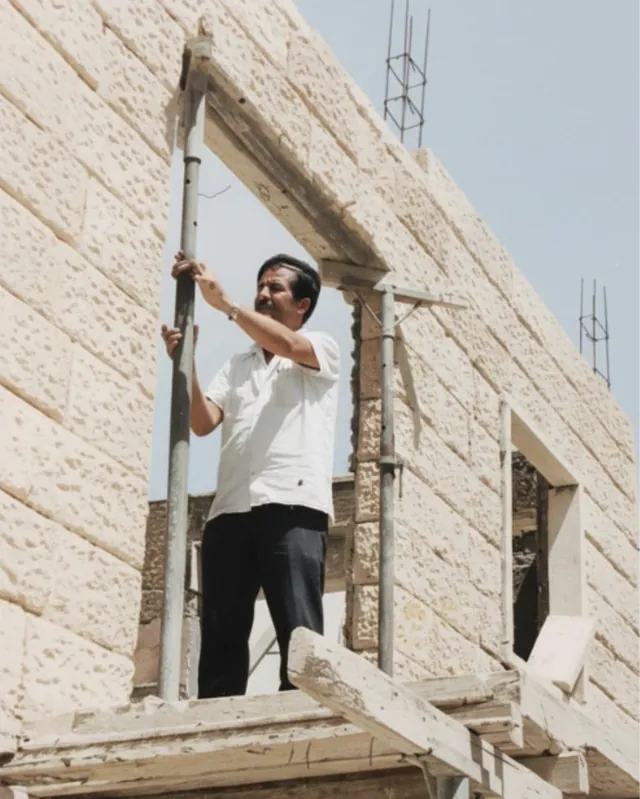 נחום אלה ז״ל עומד על פיגום ובונה קיר באבן ירושלמית, תמונה ישנה מאלבום המשפחה